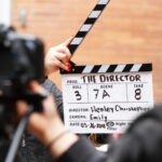 Close-up of film clapperboard in action with camera filming a take on set.