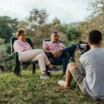 A couple being interviewed outdoors by a photographer in a lush garden setting.